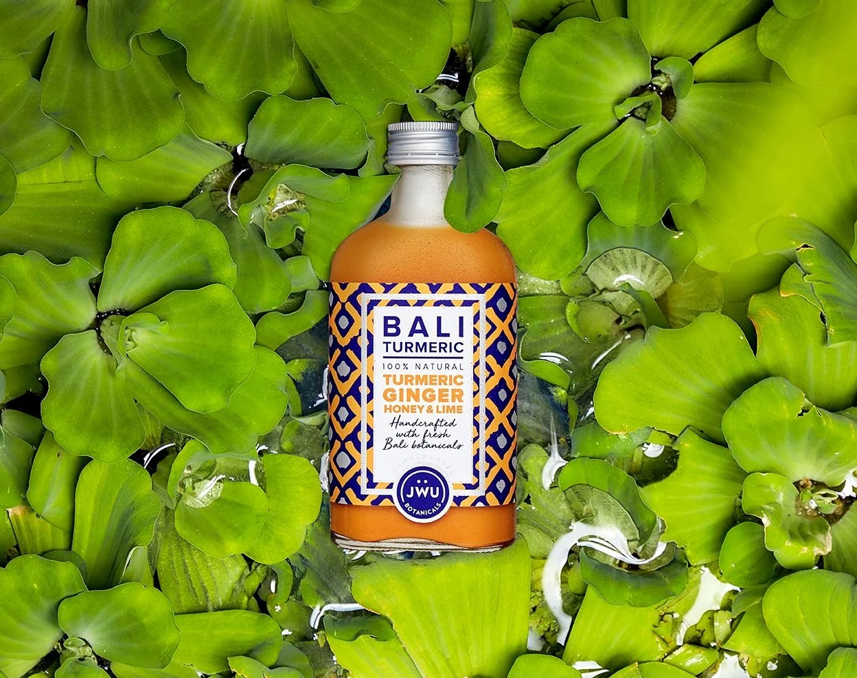 Bali Turmeric jamu bottle floating among water-lily leaves